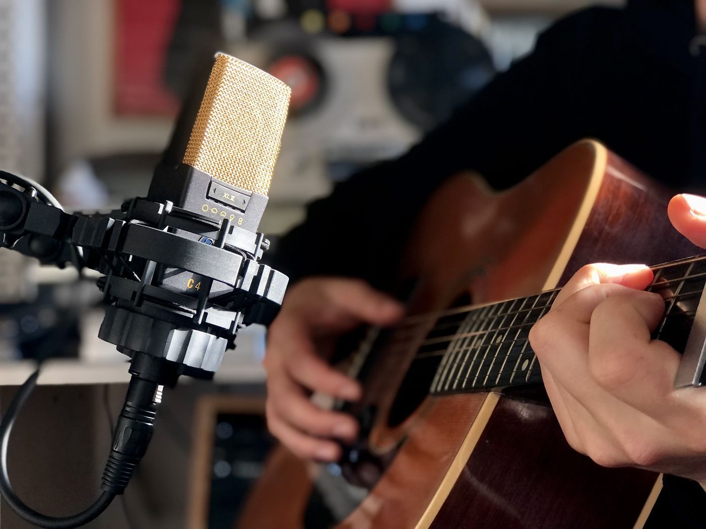 A vintage condenser microphone in front of an acoustic guitar